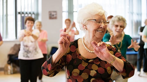 Older woman smiling as she takes part in an exercise class